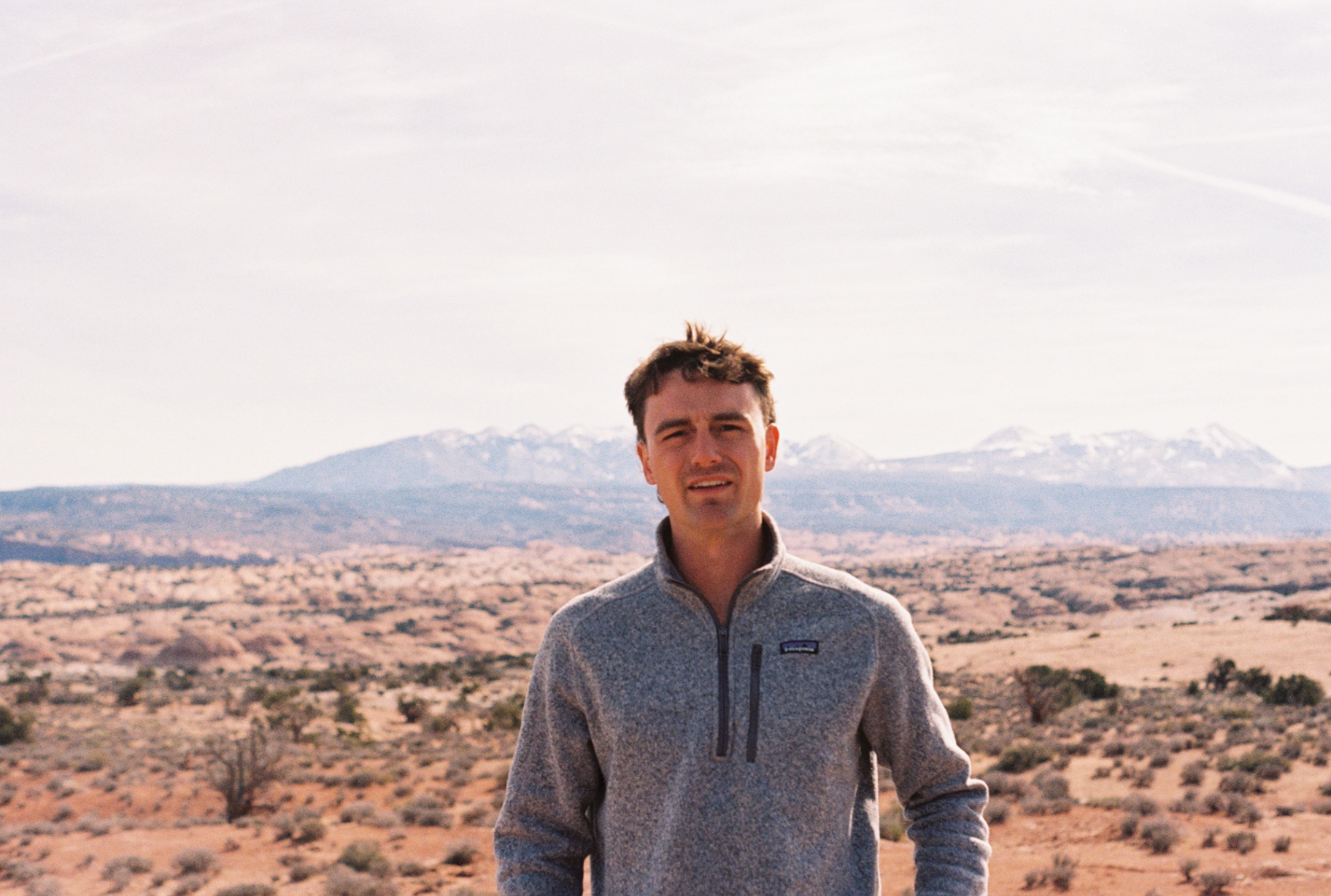 Levi Button standing in the desert with snow-capped mountains behind him